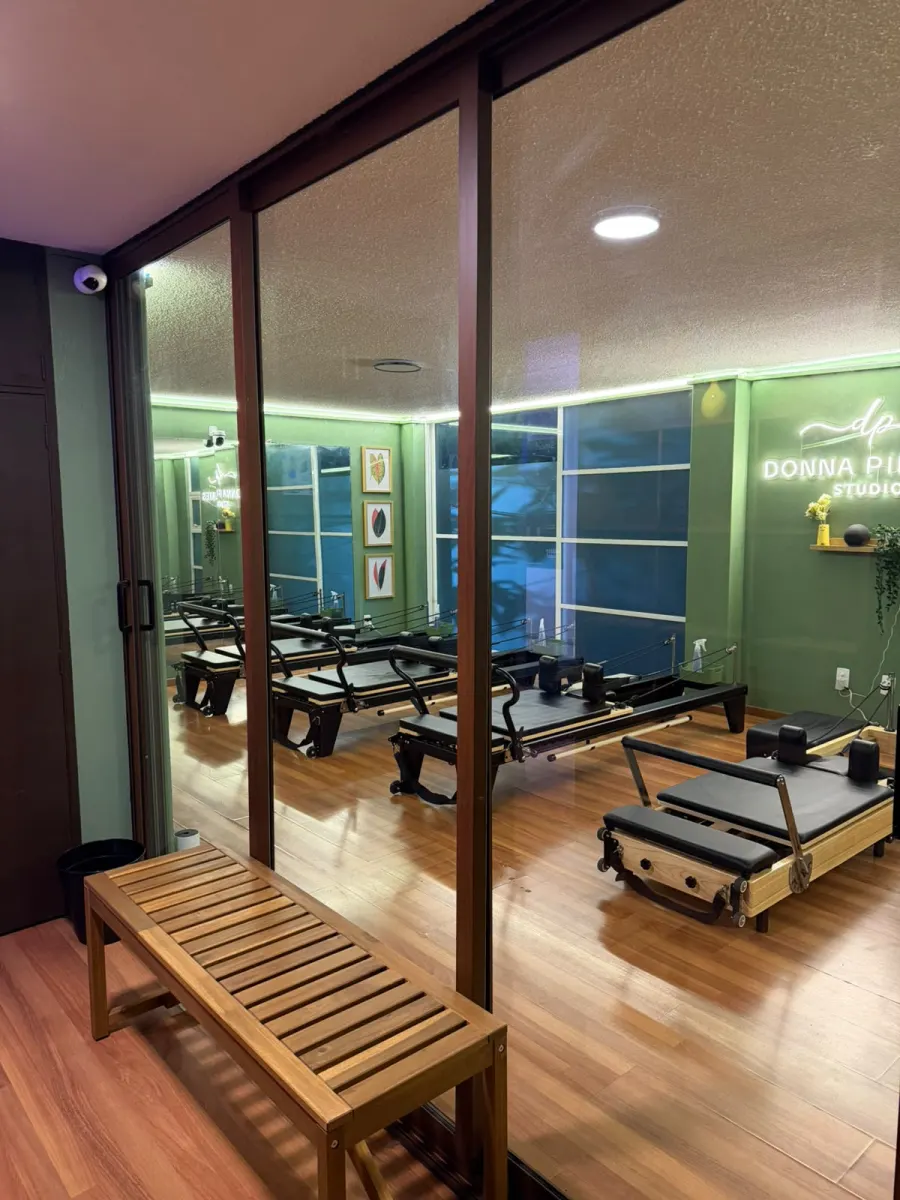 Recepción de Donna Pilates Studio con banca de madera y vista a la sala de reformers